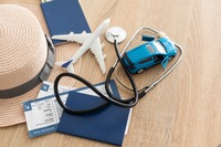 Auslandsreisekrankenversicherung Das Bild zeigt ein Stetoskop und Reiseunterlager