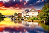 Das Bild zeigt Häuser am Wasser beim Sonnenuntergang. 
