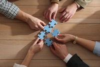 Hände halten einzelne Puzzleteile, die zusammenpassen